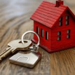 Red house model next to a key on a wooden table