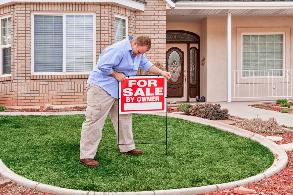 Homeowner preparing to sell property with a for sale by owner sign.
