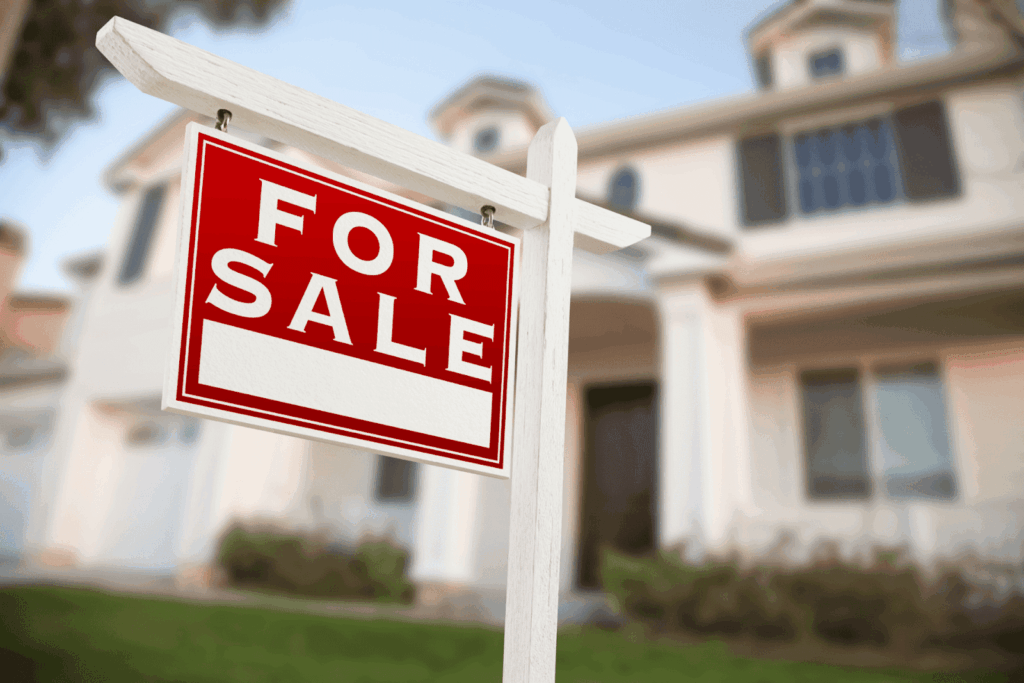 A red and white “For Sale” sign in front of a house.