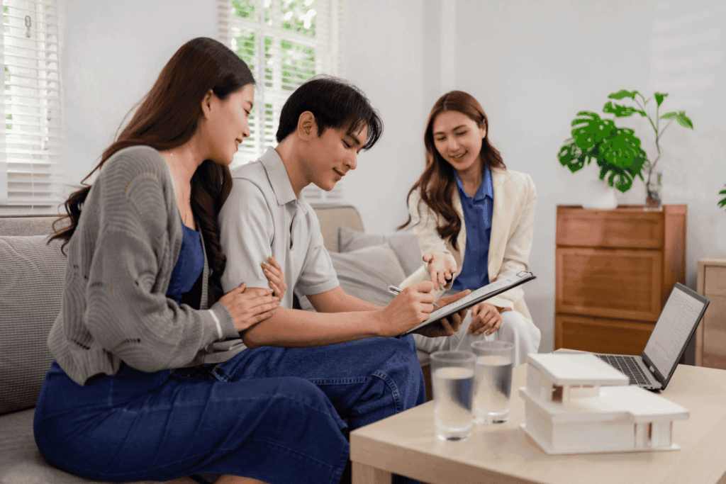 Couple signing contract with real estate agent at home