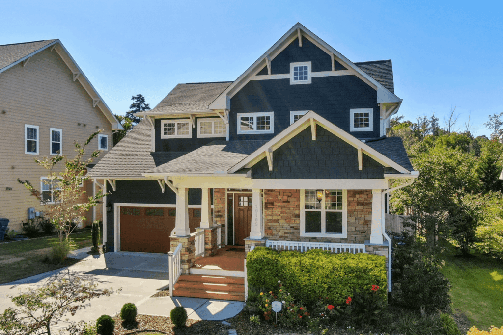 Front view of a modern two-story house with a covered porch, stone accents, and dark blue siding.