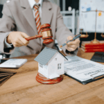 Lawyer holding a gavel beside a model house and contract documents