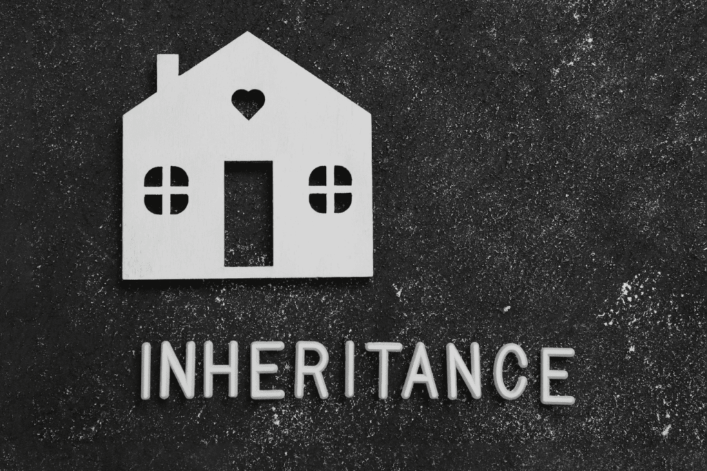 Paper house cutout above the word inheritance on a dark background