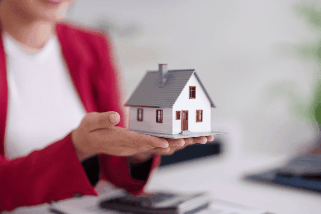 Person holding a small model house in their hands
