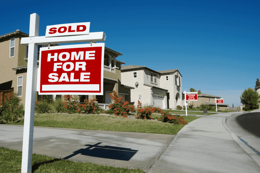 Street of houses with red ‘Home For Sale’ signs, one marked sold