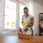 Woman wearing gloves and preparing cleaning supplies near a bright window