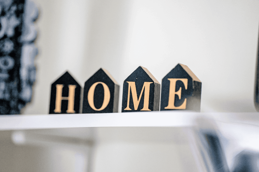Wooden house blocks spelling the word home on a shelf.