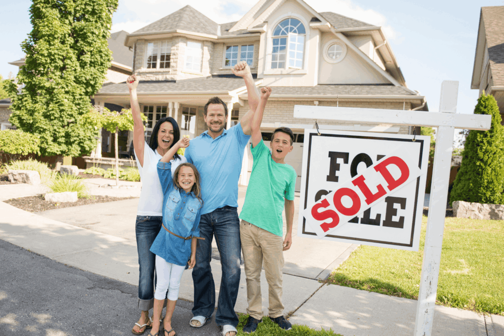 Happy Arkansas family celebrating in front of a sold home sign.
