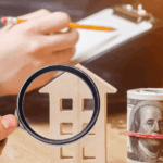 Person calculating finances with a calculator, paperwork, and stacks of cash on a desk.