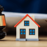 Model house beside a judge’s gavel and scales of justice, symbolizing real estate law or property legal matters.