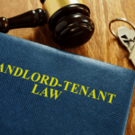 Gavel, house keys, and a book titled ‘Landlord-Tenant Law’ on a wooden table