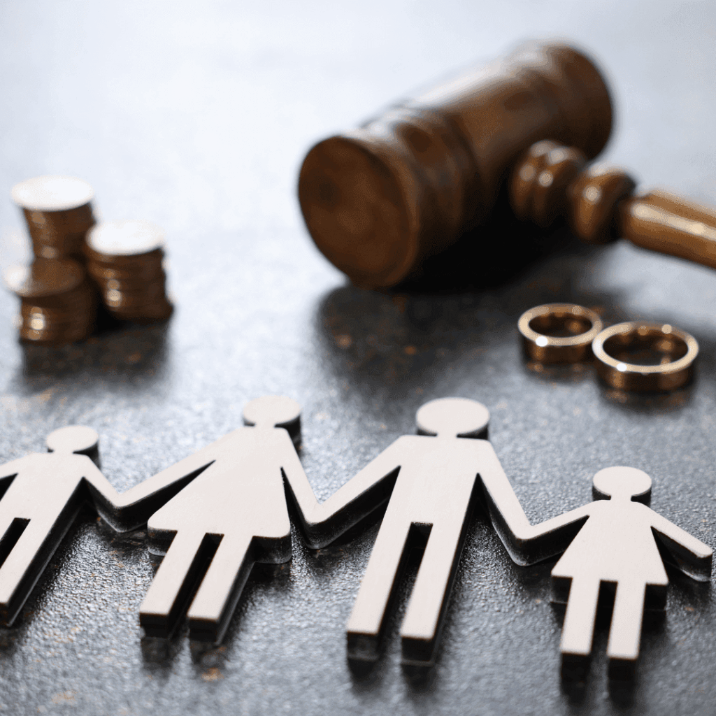 Wooden gavel, wedding rings, stacked coins, and paper cutout figures of a family holding hands, symbolizing divorce and family law.
