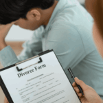 Upset man sitting beside a divorce form during a legal consultation.