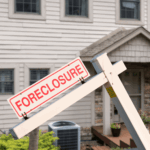 A foreclosure sign hanging on a real estate post in front of a residential home, representing mortgage default and property foreclosure proceedings.