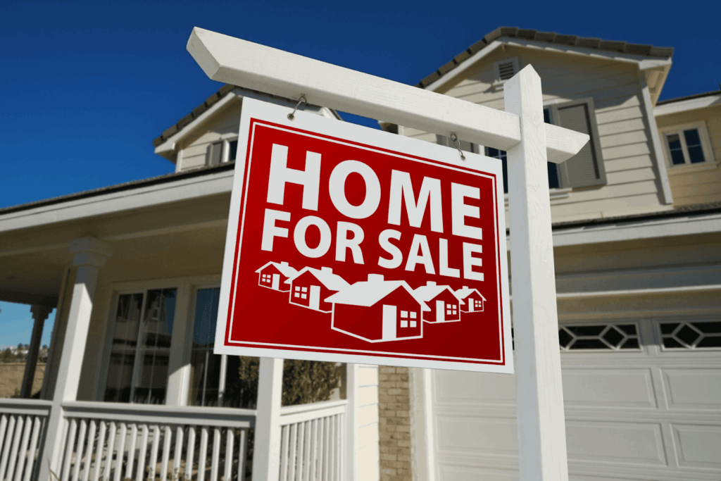  Red home for sale sign hanging in front of a modern suburban house with a porch and garage.
