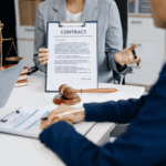 Legal professional presenting a contract to clients at a desk with a gavel and scales of justice, representing landlord laws and property sale agreements.
