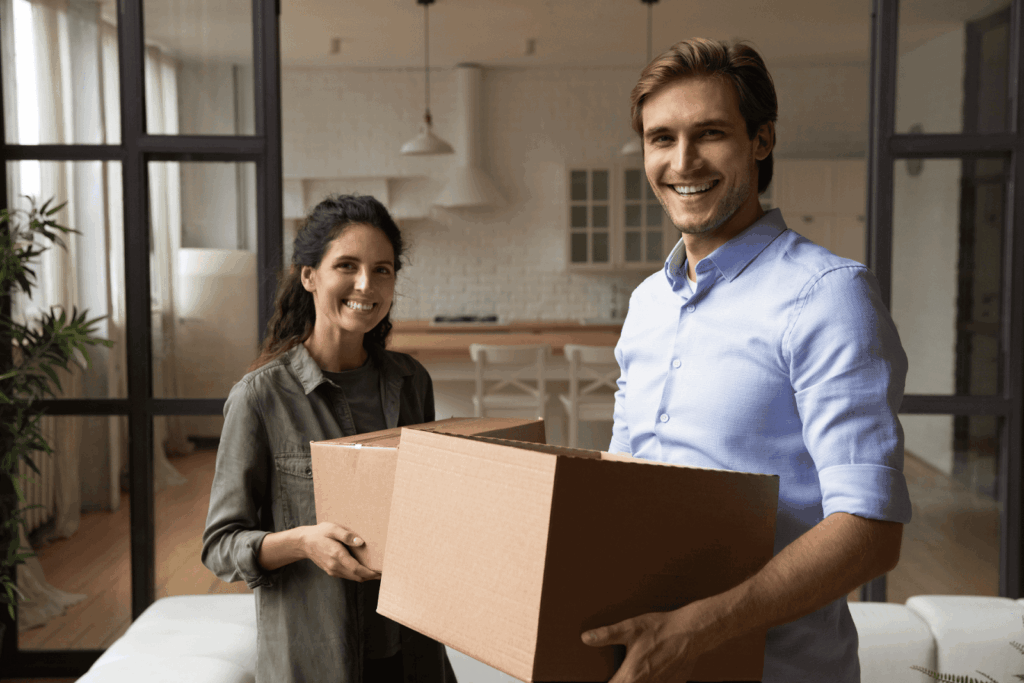 Happy renters carrying moving boxes into a new apartment, representing tenant rights and housing stability.