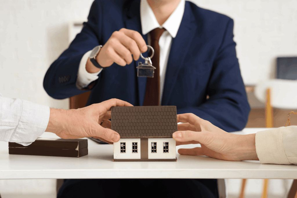 Real estate professional handing house keys as a couple completes paperwork for selling a home during divorce proceedings.