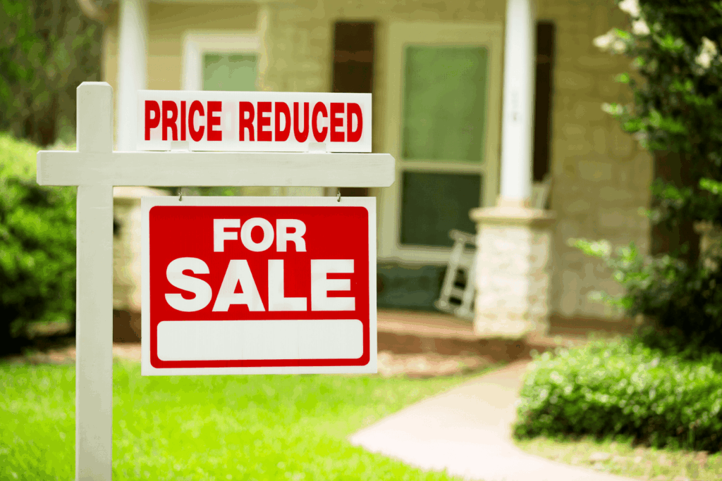  Real estate for sale sign with price reduced notice in front of a residential home.