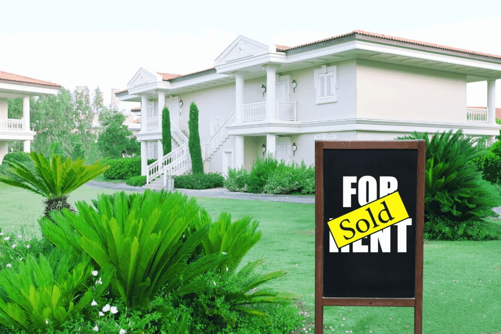 Luxury residential property with landscaped yard and real estate sign showing sold sticker.