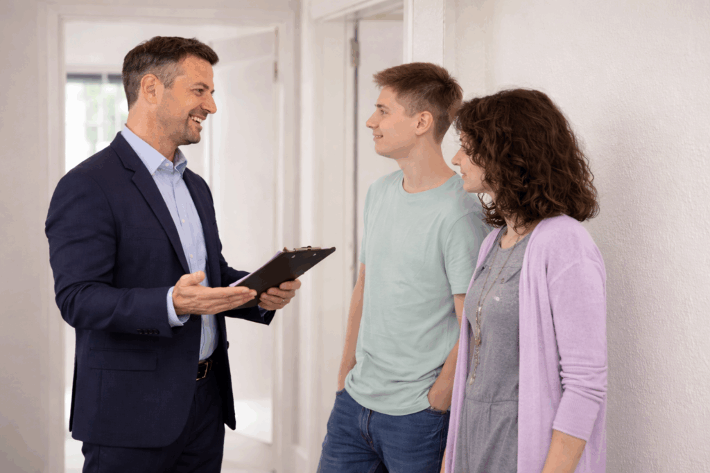  Landlord discussing property sale details with tenants inside a rental home while holding paperwork.
