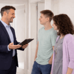 Landlord discussing property sale details with tenants inside a rental home while holding paperwork.