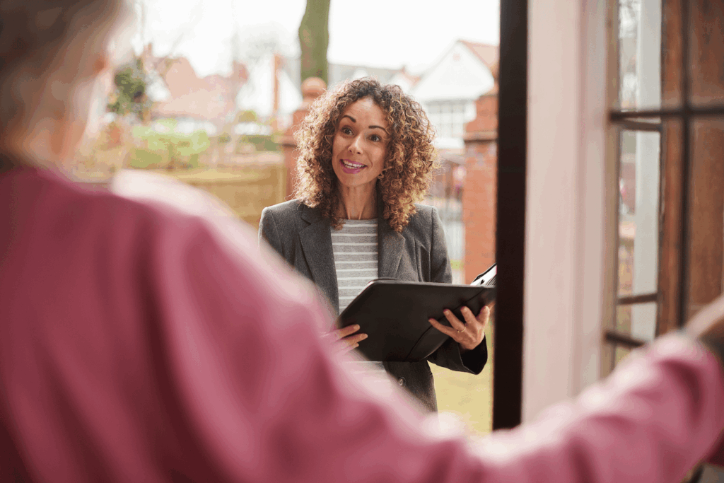 Property manager or landlord speaking with a resident at the front door while holding documents related to a property sale.