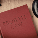 Red book titled “Probate Law” on a wooden desk beside a judge’s gavel and eyeglasses.