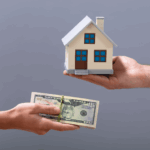 Hands exchanging cash for a small house model, symbolizing a home purchase.