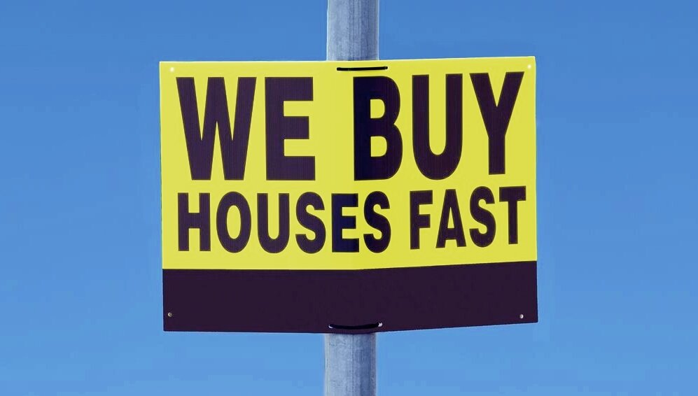 We Buy Houses words printed on a street sign, with black letters on yellow background.