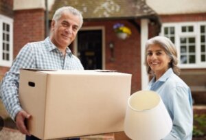 Elderly man and a woman hold house belongings during a move - downsizing.