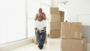 Older couple in process of moving out, sitting among cardboard boxes. Sell your house fast and move to downsize.