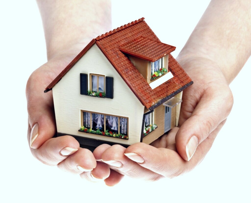 hands holding a model white house with a clay-shingled roof