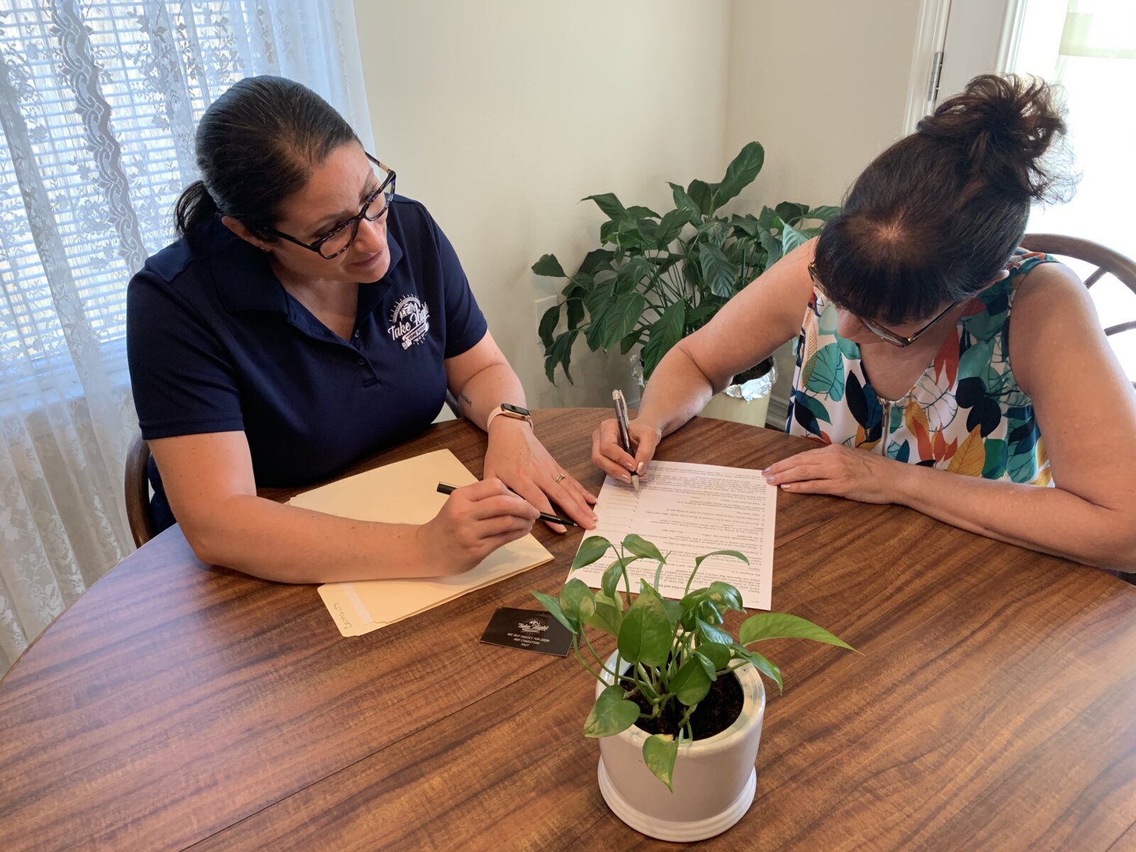 Anne and customer at table reviewing contract.