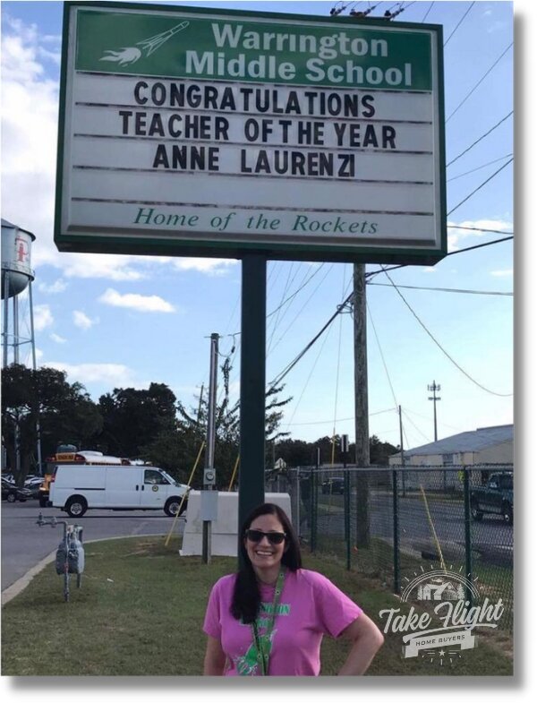 Anne in front of Warrington Middle School sign stating "Congratulations Teacher of the Year, Anne Laurenzi"