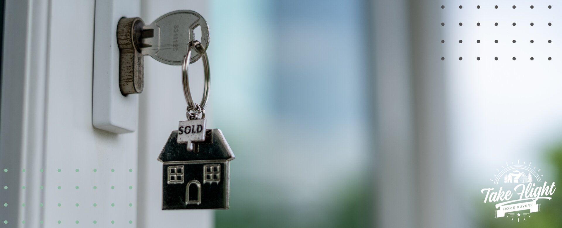 close up of door with key in keyhole and key chain shaped like a house that says "sold"