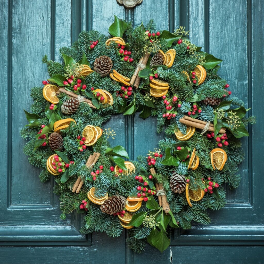 Front door fir wreath with pinecone, cinnamon sticks, dried orange slices, and red berry accents
