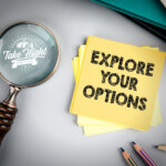 Magnifying glass on tabletop with yellow sticky note that says "explore your options."