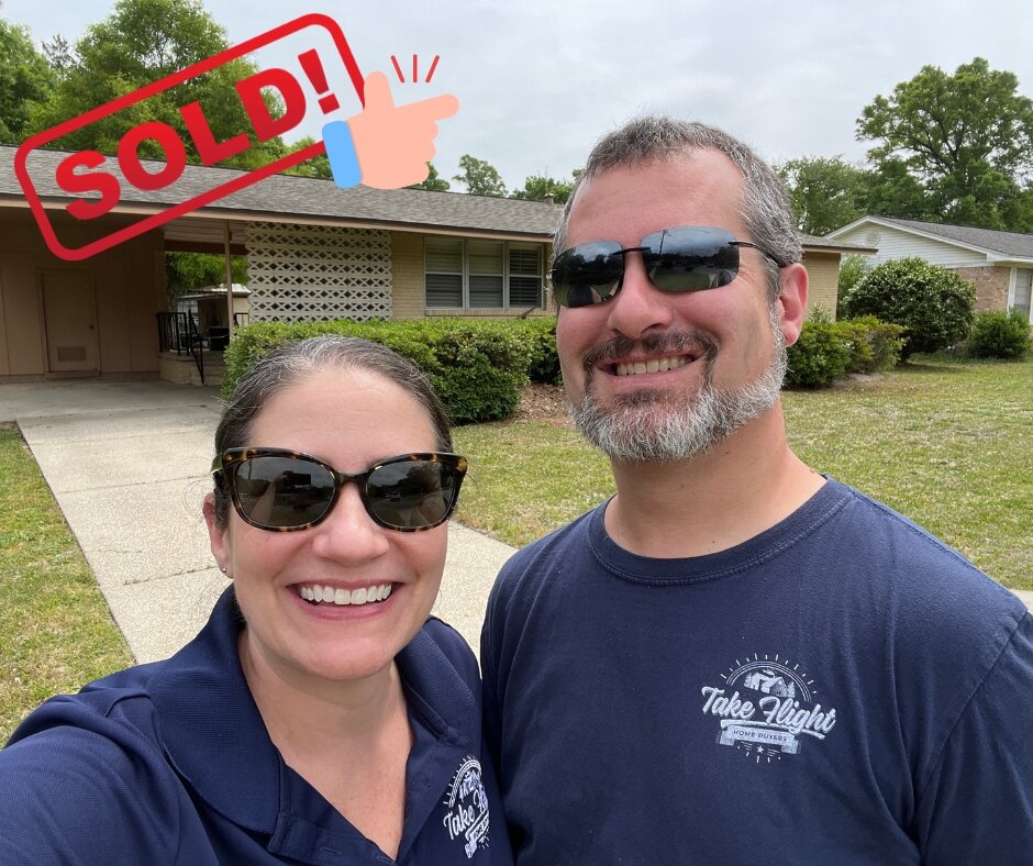 Anne & Mike in front of Pensacola house they purchased with Sold stamp graphic