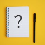 notebook with large question mark and pen against yellow background