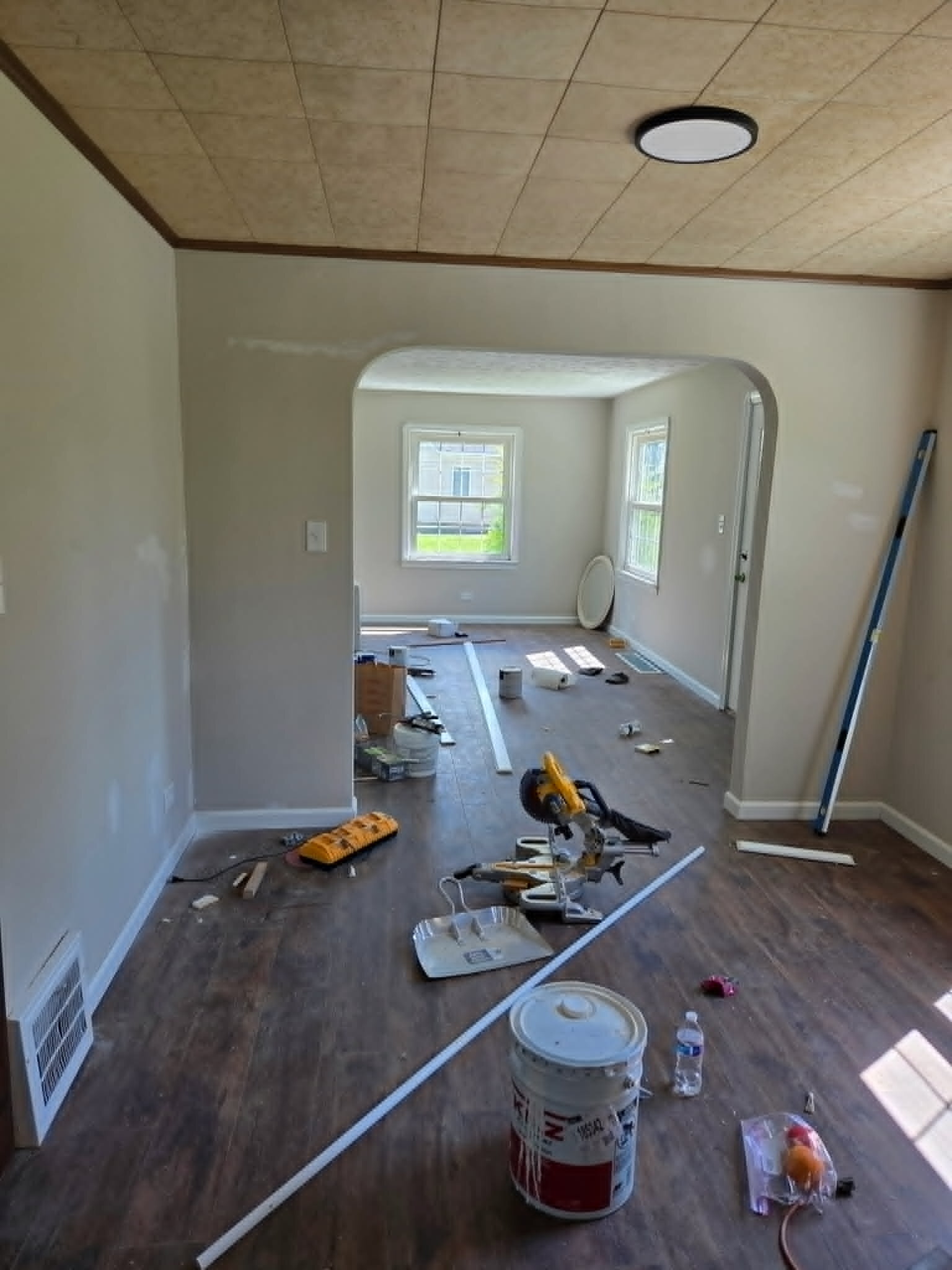Living room with fresh paint, flooring, trim materials, and tools during an Oakwood Village renovation.