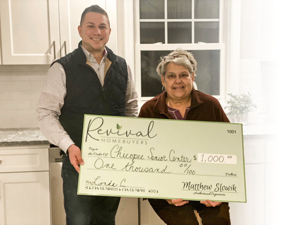 This is a photo of Matt, the owner of Revival Homebuyers, and a home seller, showing a big check, which was for a donation by Revival Homebuyers to the Chicopee Senior Center in Chicopee MA in honor of the sellers father.