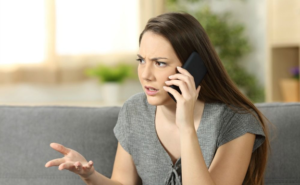 Frustrated woman on a phone call, possibly dealing with challenges while selling your property, expressing concern while sitting on a couch.