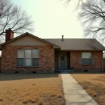 A single-story brick house with a dry lawn and mature trees, representing the process of selling inherited property in its current condition