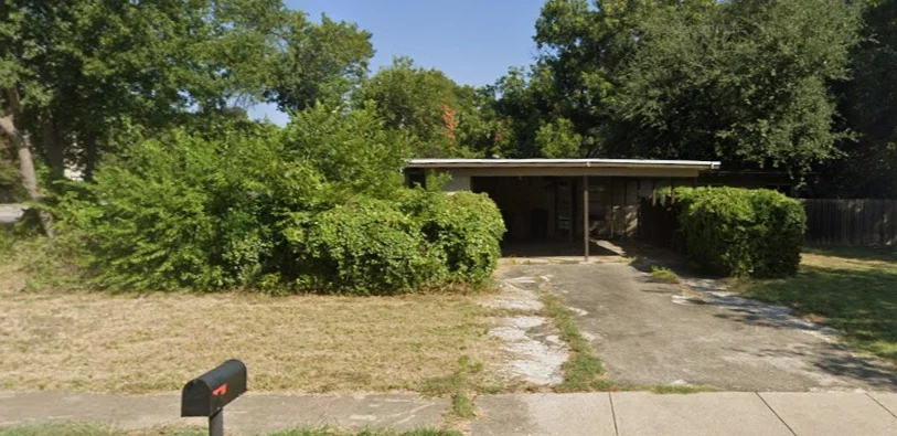 vacant house with overgrown bushes and neglected yard