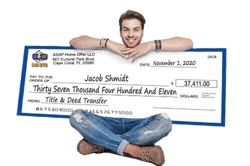 a man sitting and holding onto a large check