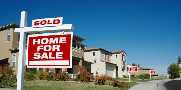 a row of houses on a street with for sale sign in their front yard
