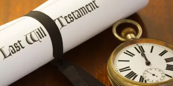 a rolled up last will and testament beside an old vintage watch