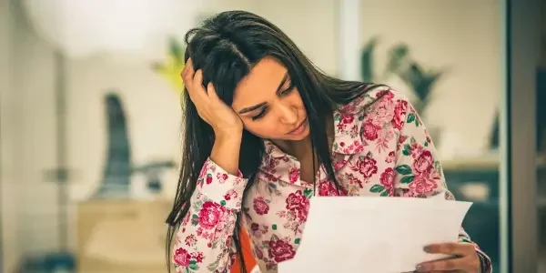 At her desk, a woman reviews a document, thinking about how can you stop a foreclosure