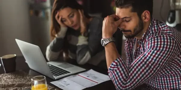 a couple seated in front of a laptop looking stressed after receiving the notice